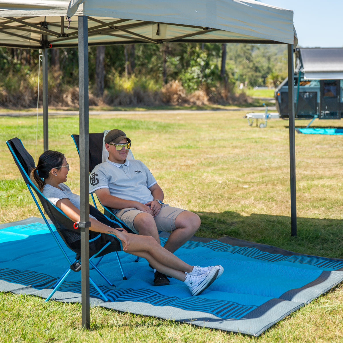 Two people in camping chairs enjoying the shade of the gazebo.